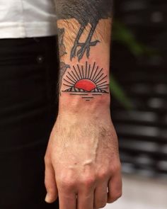 a man's arm with a bird and sun tattoo on the left side of his wrist