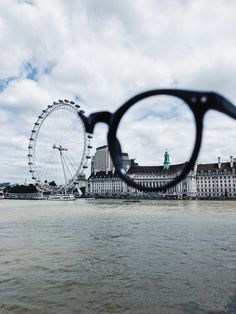 a ferris wheel seen through a pair of eyeglasses in front of the water