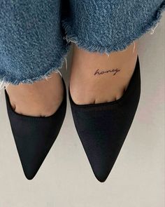 a woman's feet with her name tattooed on the ankle and heels in front of her