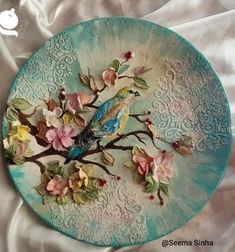 a plate with flowers and birds painted on the side is sitting on a white sheet