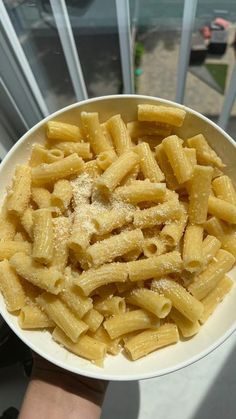 a white bowl filled with macaroni and cheese on top of a window sill