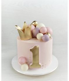 a pink cake with gold decorations and a number one on top