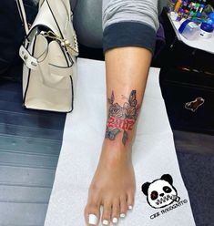 a woman's foot with a tattoo on it and a handbag next to her