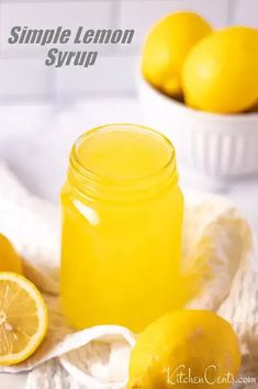 a glass jar filled with lemon syrup on top of a white cloth next to some lemons