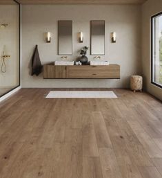 a large bathroom with wooden floors and mirrors on the wall, along with two sinks