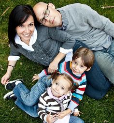 two adults and one child are laying on the grass with their arms around each other