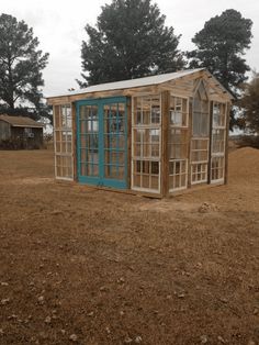 a small wooden shed sitting in the middle of a field with windows on it's side