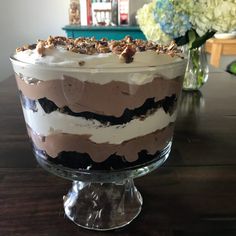 a large layered cake sitting on top of a wooden table next to a vase with flowers