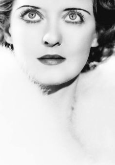 black and white photograph of a woman with large blue eyes wearing fur collared coat