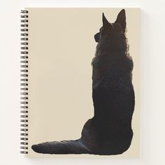 a black dog sitting on its hind legs in front of a white background spiral notebook