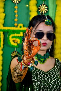 a woman holding up her hands with henna on it's palms and wearing sunglasses