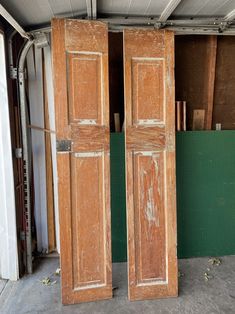 two wooden doors sitting inside of a garage