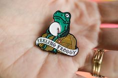 a person holding a pin with a frog on it