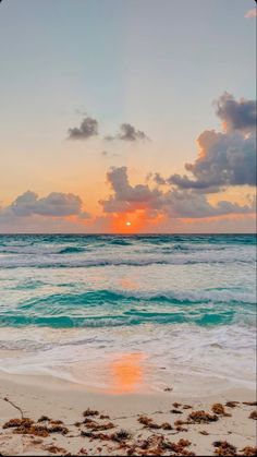 the sun is setting over the ocean with clouds in the sky and waves on the beach