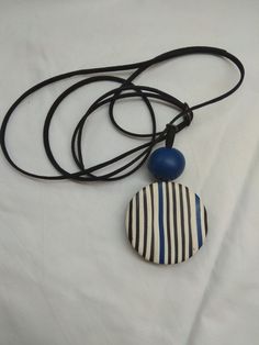 a black and white striped necklace with a blue bead hanging from it's end