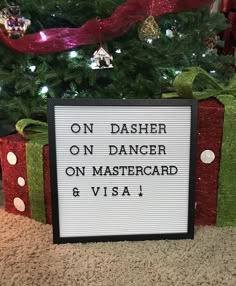 a sign that says on dasher on dancer on mastercard and visa in front of a christmas tree