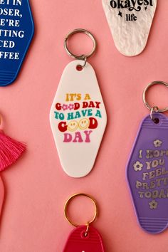 four different colored keychains on a pink background with the words it's a good day to have a good day