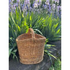 a wicker basket sitting in front of purple flowers