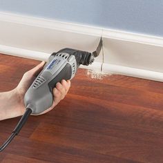 a person using a power drill to fix a hole in the wall