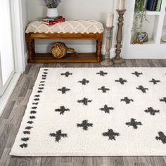 a white rug with black bees on it in front of a wooden bench and bookshelf