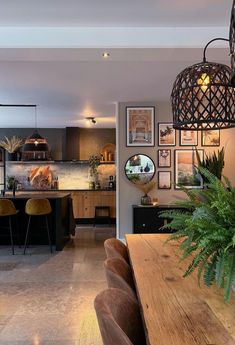 a dining room table and chairs with pictures on the wall behind it in an open concept kitchen