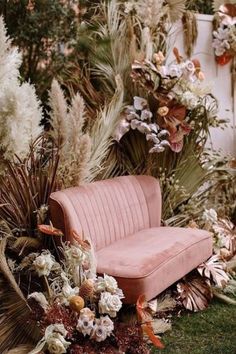 a pink couch surrounded by flowers and plants