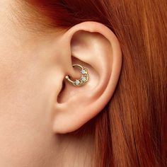 a woman with red hair wearing a pair of ear piercings on her left side