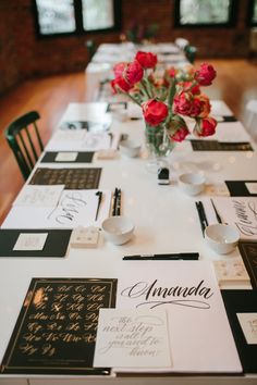 the table is set with place cards and flowers in vases on top of it