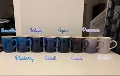 six coffee mugs with different colors and names on the cups in front of them