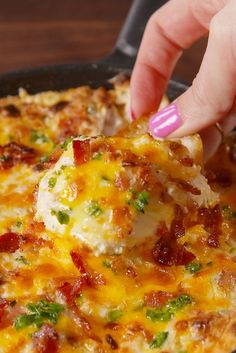 a person dipping something into a skillet with cheese and broccoli on it