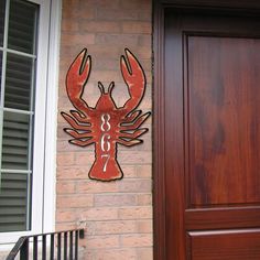 a wooden door with a metal lobster sign on the side and numbers painted on it