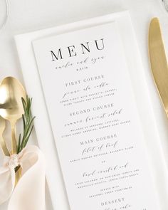 a table setting with silverware and a menu card on it, along with gold utensils