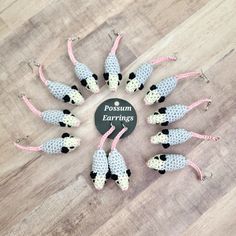 a group of knitted mice sitting on top of a wooden floor next to a sign that says possum earings