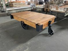 a wooden table sitting on wheels in a warehouse