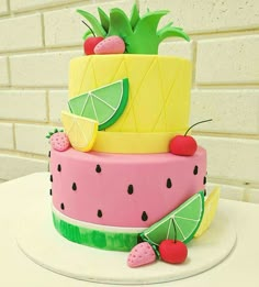 a three tiered cake decorated with pineapple, watermelon and lime slices