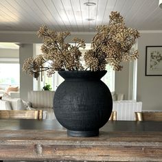 a black vase filled with flowers sitting on top of a wooden table in a living room