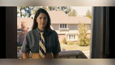 a woman wearing a tie standing in front of a window