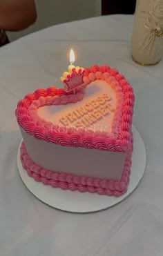 a heart shaped cake with a lit candle in the shape of a heart on a table