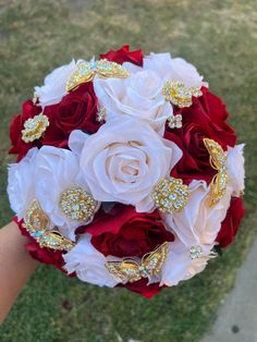 a bridal bouquet with red and white roses, brooches, and jewels