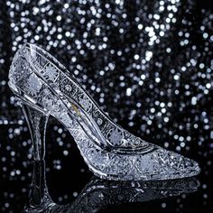 a pair of high heeled shoes sitting on top of a glass table covered in glitter