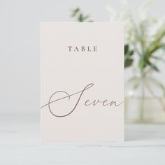 a table card with the word'seven'written in cursive writing on it