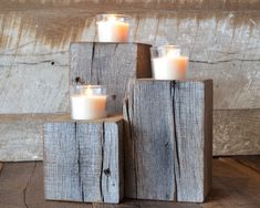 three wooden blocks with lit candles in them