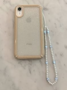 an iphone case sitting on top of a marble table next to a beaded necklace