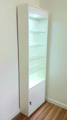 an empty room with white shelves and wood flooring