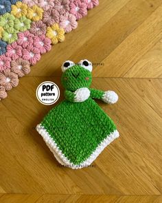 a crocheted frog is sitting on the floor