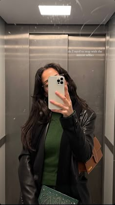 a woman taking a selfie in an elevator with her cell phone up to her face