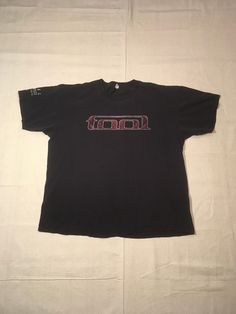 "vintage TOOL t-shirt Alex Gray eyes art TOOL written across chest TOOL Los Angeles California on arm band cosmic eyes on back w/TOOL written in center front/back print Anvil tag, pre-shrunk cotton black w/red/white print good vintage condition w/light wear fade, small holes, see photos label size worn off, tag is partly gone, see below measures, lying flat, shoulder-22 1/2\" sleeve-7 1/2\" chest-23\" length-28\"" Tool Shirt Band, Baggy Band Tee, Tool Band Art, Tool Shirt, Vintage Band Shirts, Vintage Band T Shirts, Skater Outfits, Eyes Art, Tool Band