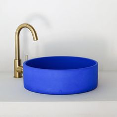 a gold faucet sits next to a blue bowl on a white countertop