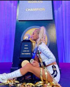 a woman sitting in front of a trophy with her legs crossed and wearing gold ribbons around her ankles