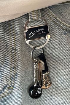 a bottle opener with a keychain attached to it's back pocket, in front of a pair of jeans